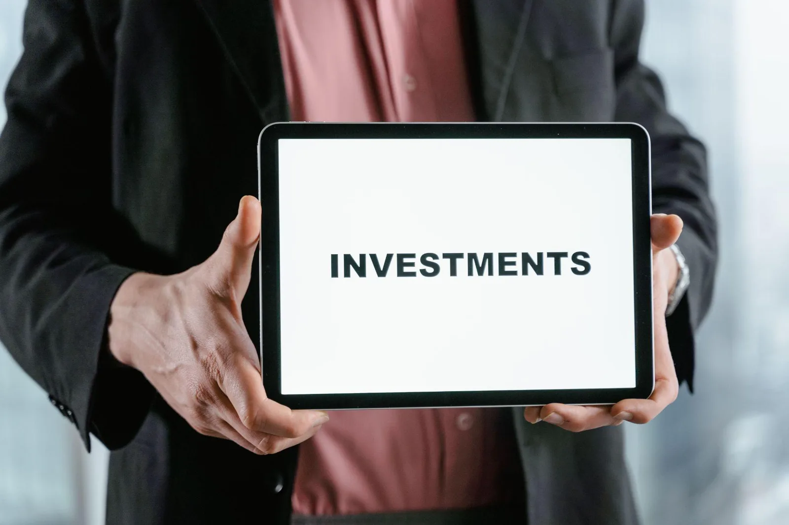 Businessperson holding a tablet displaying the word investments