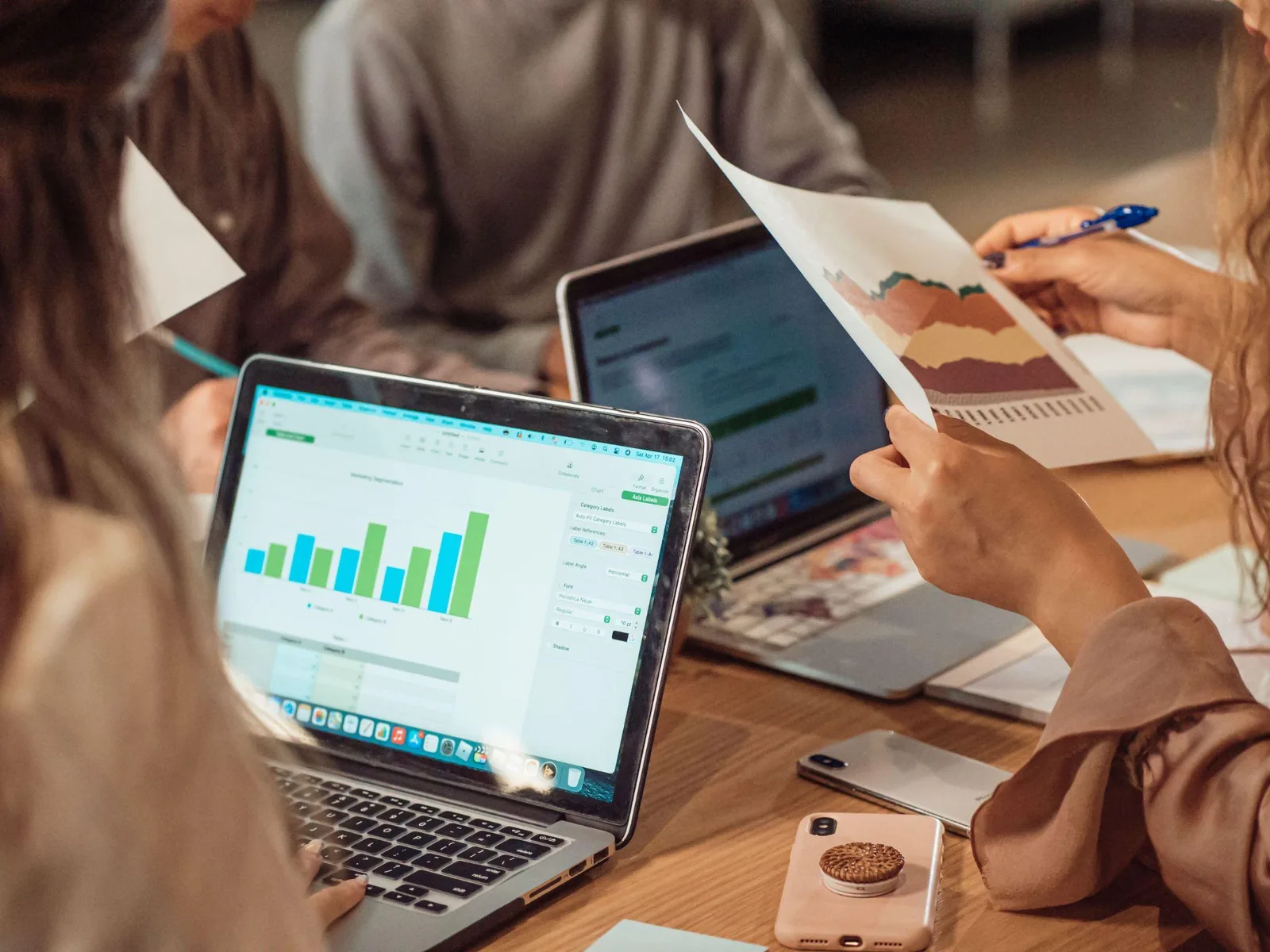 Team reviewing printed charts and a laptop spreadsheet during a marketing performance meeting
