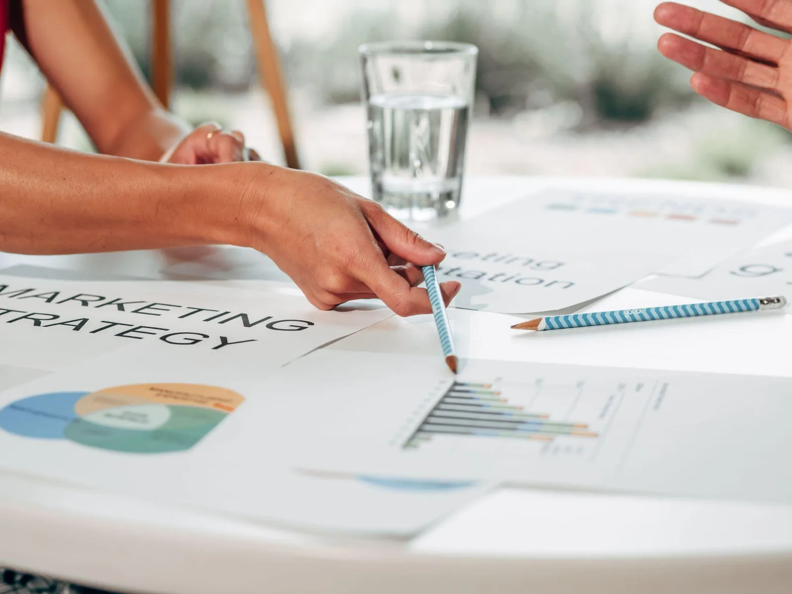 Marketers annotating a printed marketing strategy document with charts on a white table