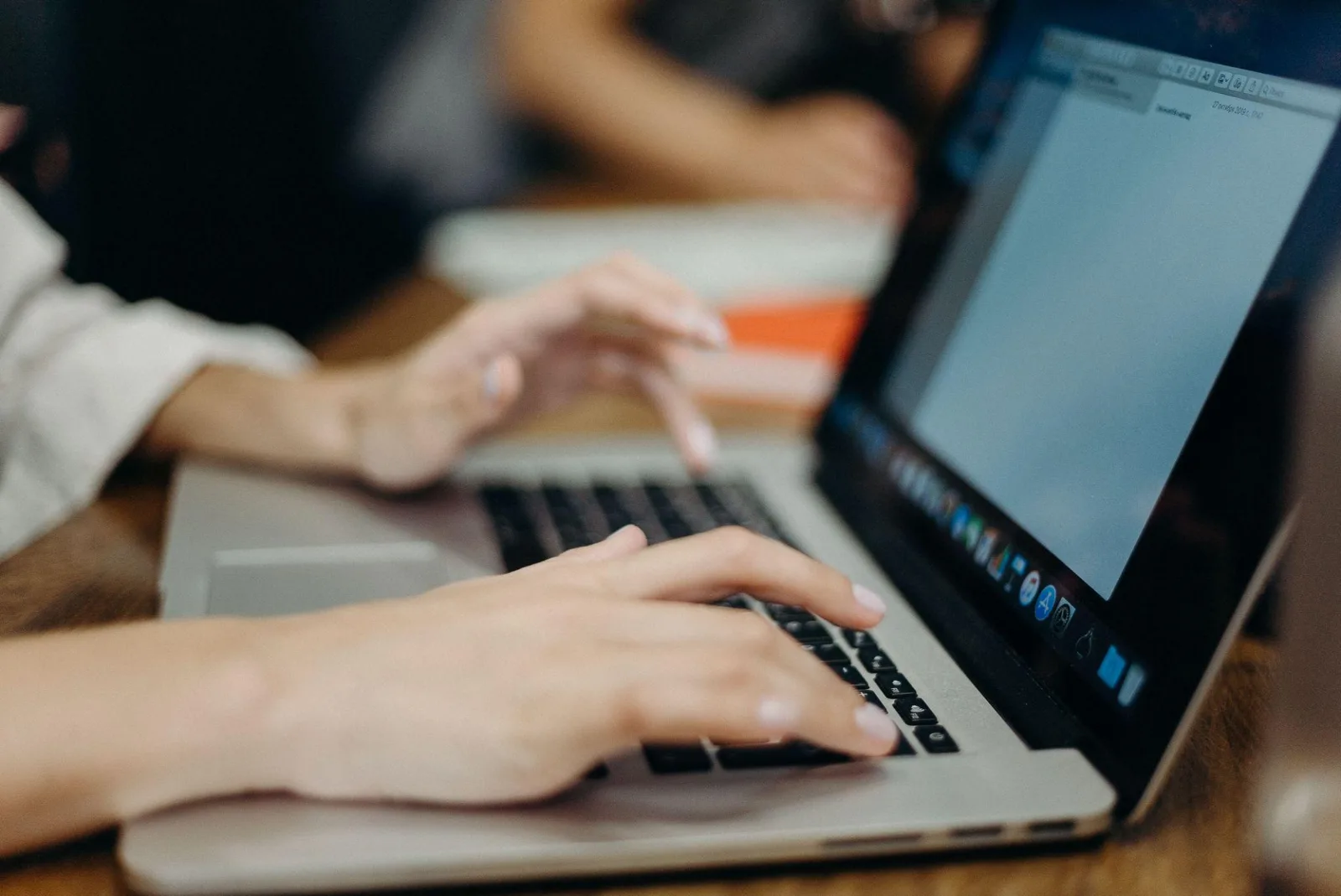 Two people working side by side on laptops at a shared desk
