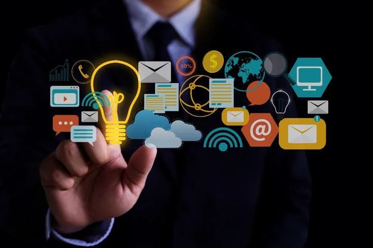 Content ideas concept with a hand touching a lightbulb surrounded by digital media icons